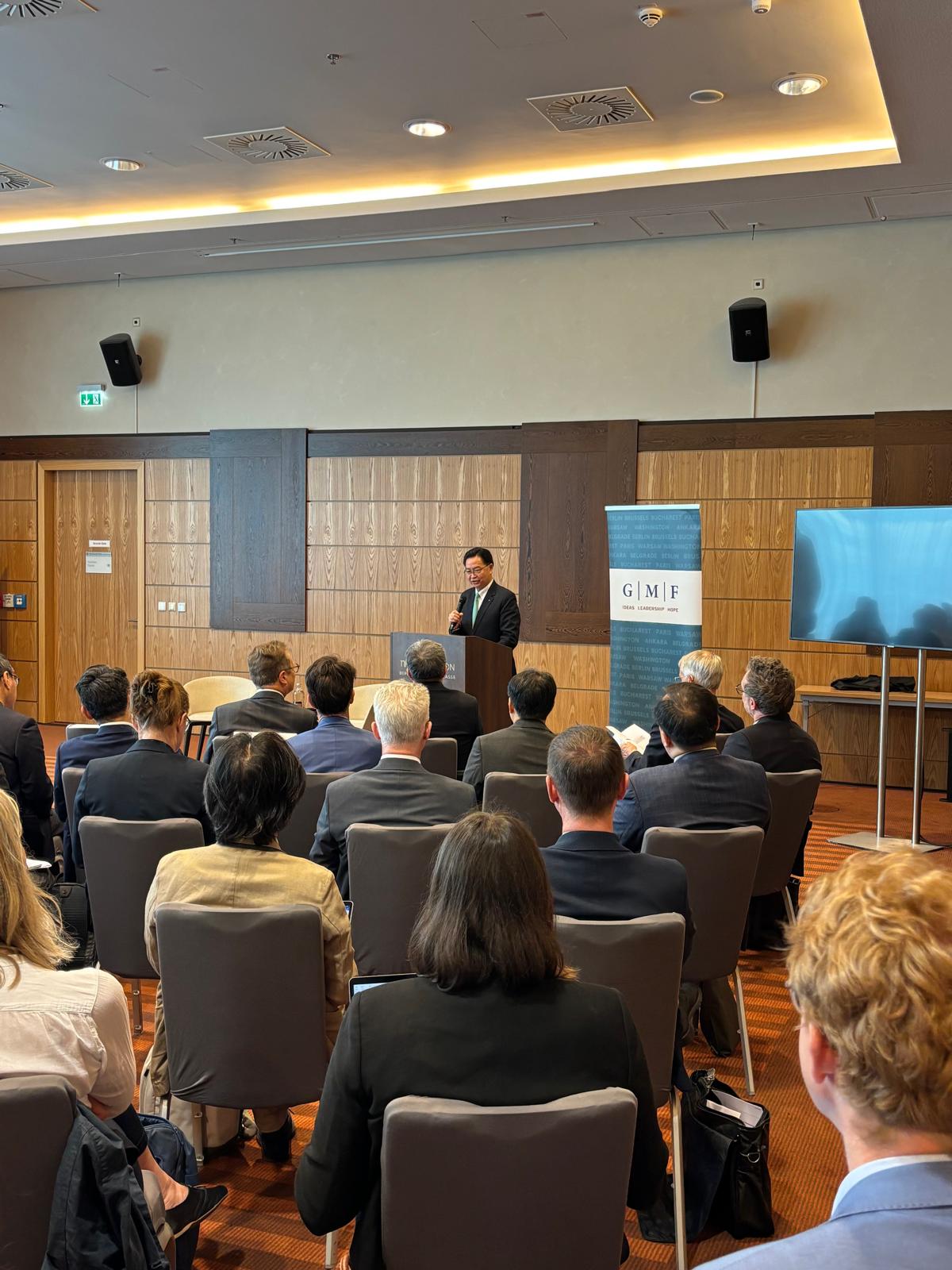 Taiwanese man in a suit speaking at a podium