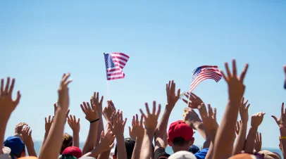 Group of People Waving American Flags over blue sky