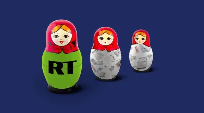 Line of Russian nesting dolls on a blue backdrop. The first doll has logo for RT on it, and the other two have graphics of newspapers on their bodies