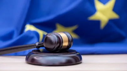 Gavel on a table with an EU flag behind it 