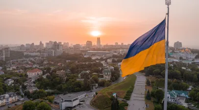 Ukrainian flag flying over an urban skyline at dawn