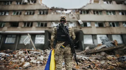 Ukrainian military woman with the Ukrainian flag in her hands on the background of an exploded house