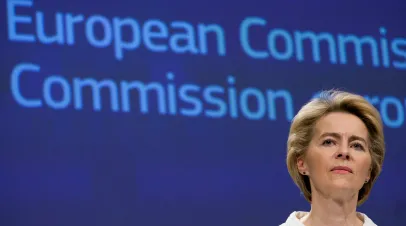 Urusla Van der Leyen standing with a European Commission sign behind her