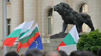 People waving Bulgarian flags under a statue of a lion