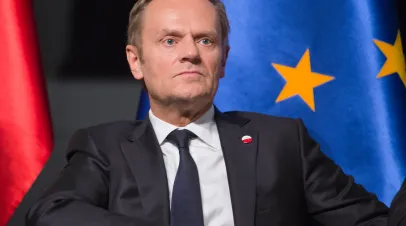 Polish PM Donald Tusk sitting in front of the Polish and EU flags