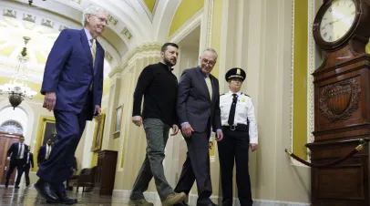 Ukrainian President Zelenskyy walking down a hallway flanked by Senate Leaders Mitch McConnell and Chuck Schumer