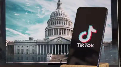 Picture of phone with the tiktok logo in the foreground with the US congress in the background