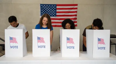 Row of people bending over voting privacy barriers 