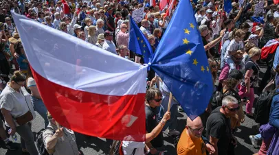 A crowd of marchers hoisting Polish and EU flags