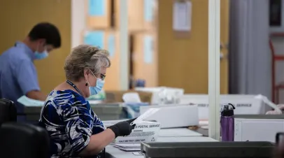 Female election worker handling ballots 