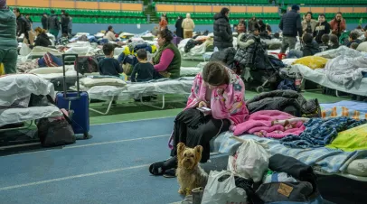 chisinau, moldova - march 4 2022: ukrainian refugee girl looking in smartphone with dog next to her at the chisinau arena refugee center.