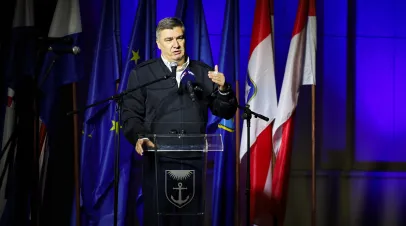 Zoran Milanović standing at a podium in front of some flags