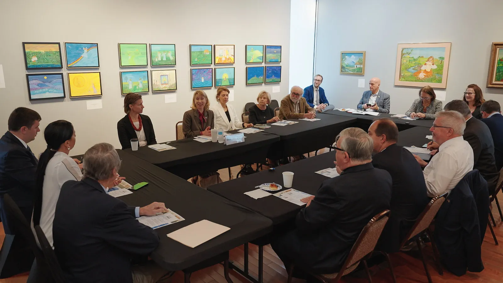 People sitting around a circle of tables inside an art gallery